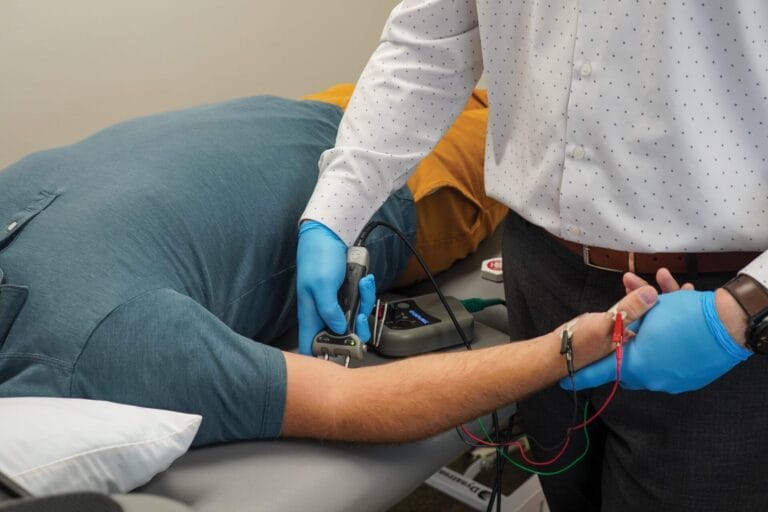 Doctor using EMG to assess patient nerves in arm
