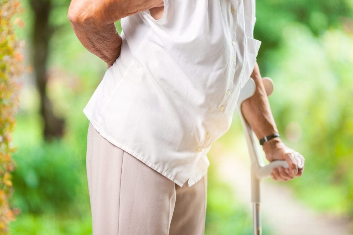 Elderly woman outdoors with lower back pain
